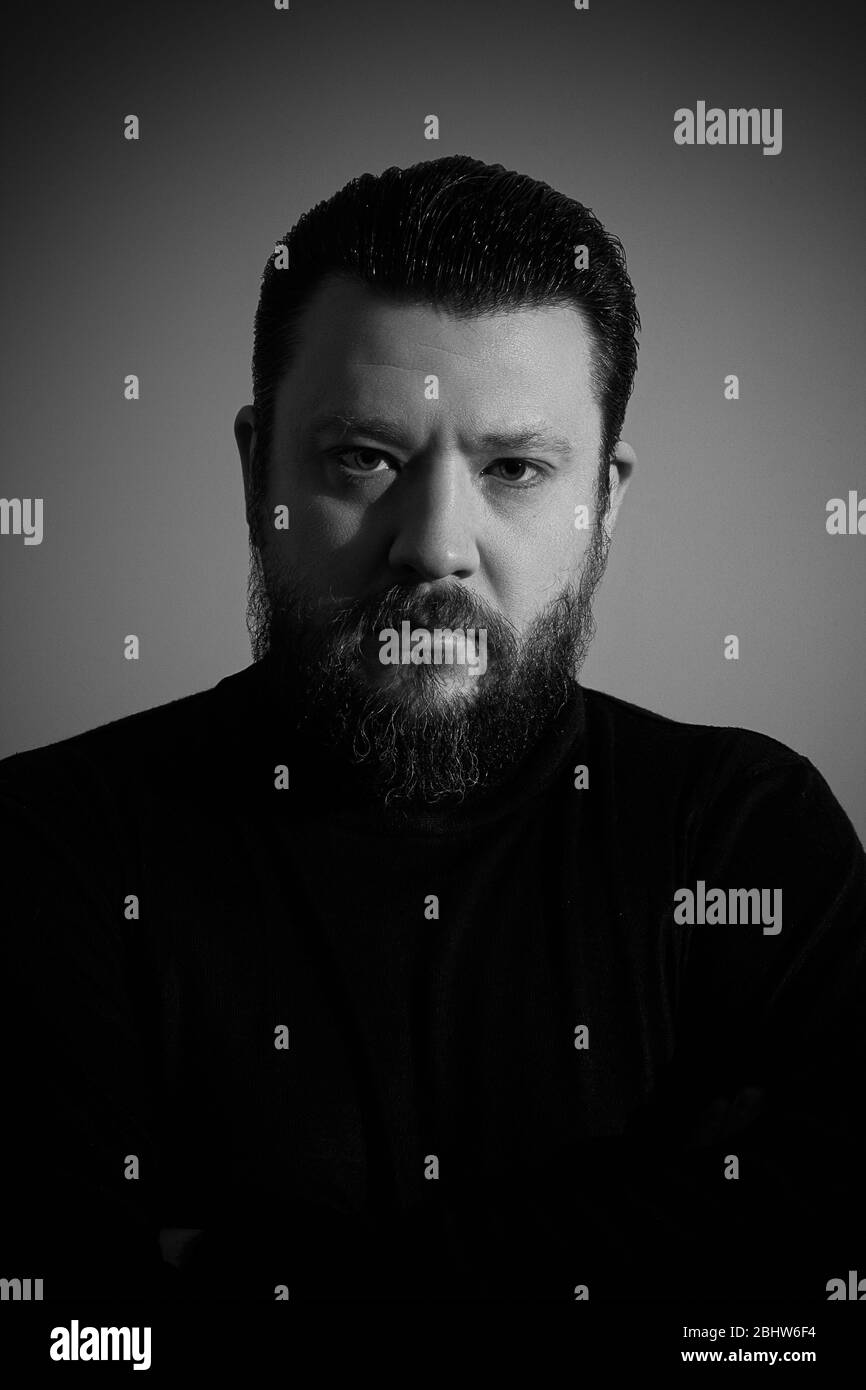 Ritratto in studio in bianco e nero di brutale uomo barbuto in dolcevita Foto Stock