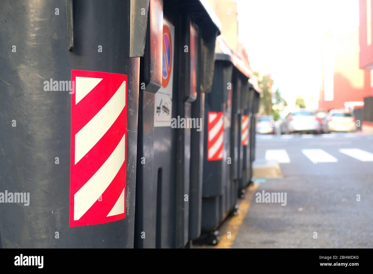 Contenitori per rifiuti in plastica nera contrassegnati con nastro retroriflettente, apparecchiature per la gestione dei rifiuti urbani. Foto Stock