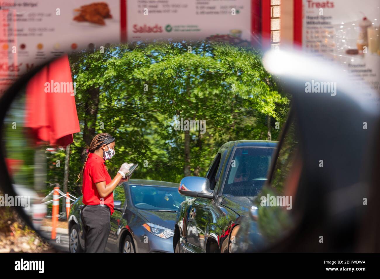Un dipendente che osserva le linee guida di sicurezza COVID-19 mentre effettua gli ordini drive-thru presso un ristorante Chick-fil-A di Metro Atlanta, Georgia. (STATI UNITI) Foto Stock
