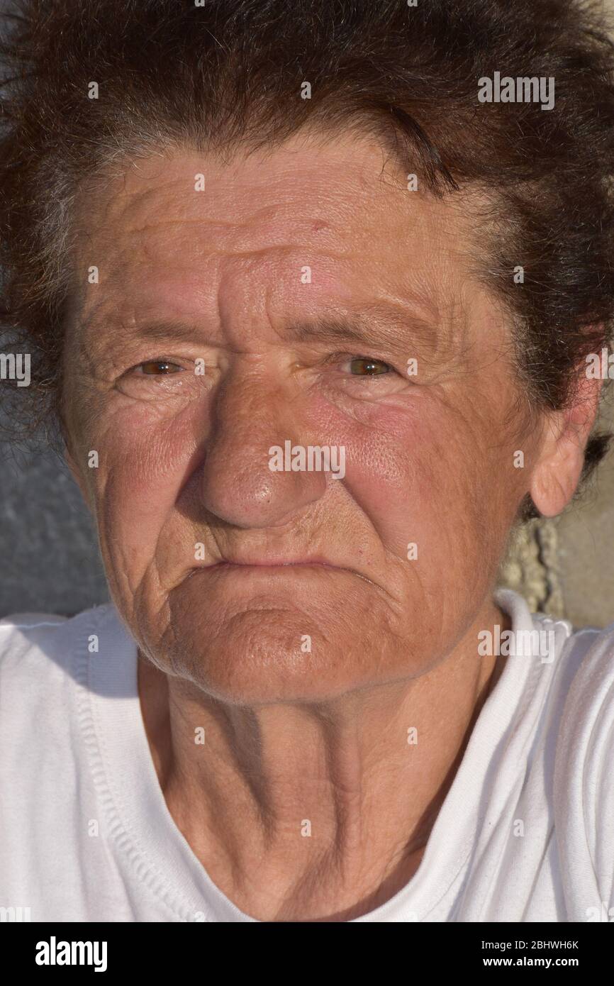 Il volto di una donna anziana con rughe illuminate al sole Foto Stock