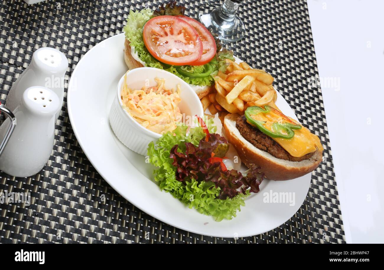 Piatto di hamburger aperto servito con insalata di cavolo e patatine fritte Foto Stock
