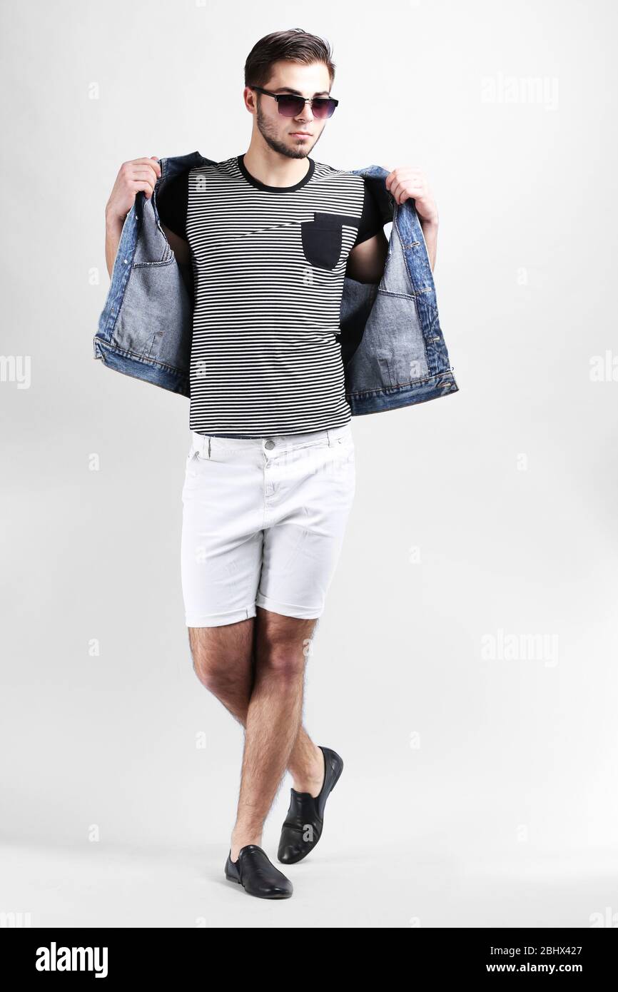 Uomo in pantaloncini bianchi e jeans giubbotto su sfondo grigio Foto stock  - Alamy