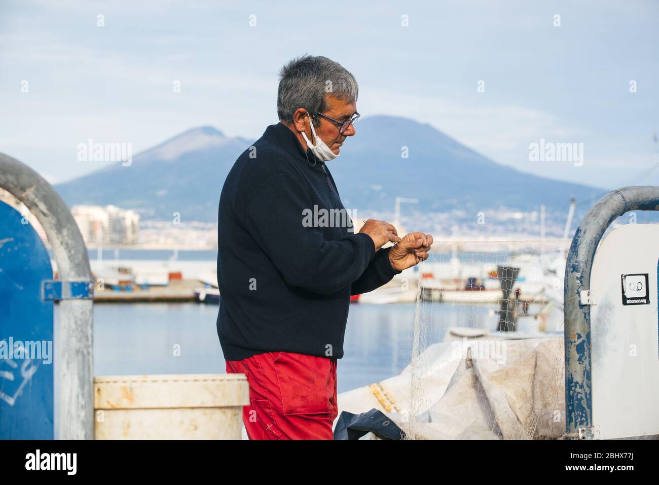 Napoli, Italia. 26 aprile 2020. Un pescatore che indossa una maschera facciale come misura preventiva, durante il blocco.a seguito della covid19 pandemia che ha colpito fortemente l'Italia, il primo Ministro, Giuseppe Conte ha ordinato forti restrizioni per la quarantena per minimizzare la diffusione del virus corona. Credit: SOPA Images Limited/Alamy Live News Foto Stock