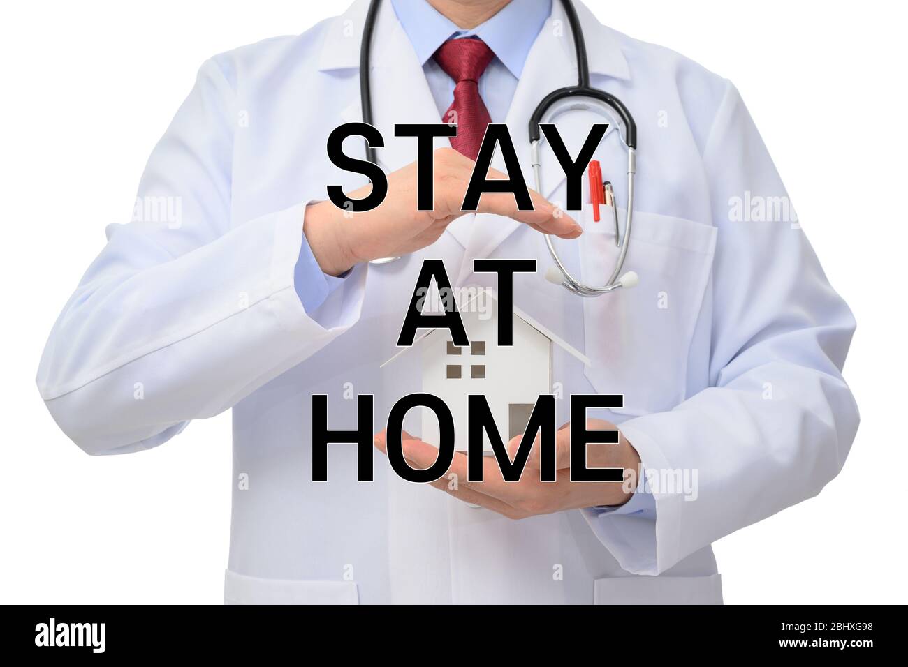 Rimani a casa. Dottore in possesso di un modello di casa su sfondo bianco Foto Stock