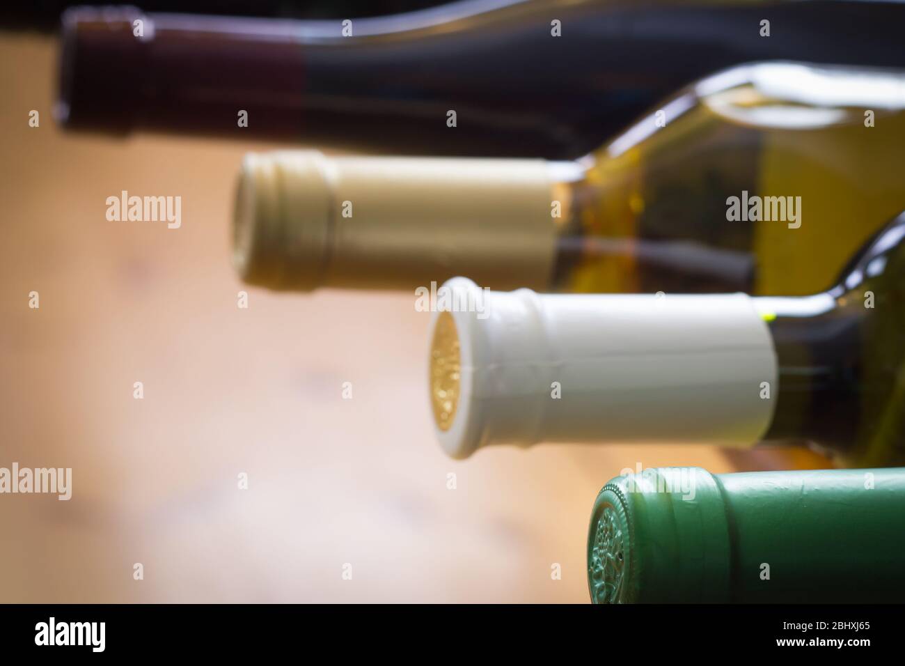 Bottiglie di vino impilate su scaffali di legno sparate con profondità di campo limitata, concetto di alcol Foto Stock