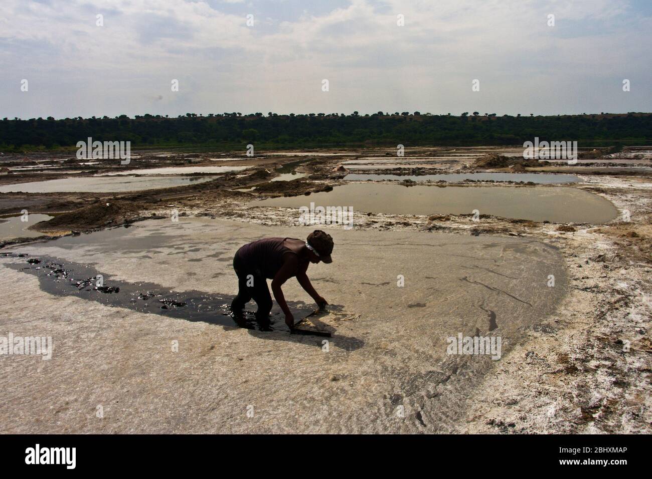 La raccolta di sale dalle padelle di evaporazione nel lago di soda nel cratere di Bunyampaka è un lavoro di ritorno ma un reddito stagionale prezioso Foto Stock