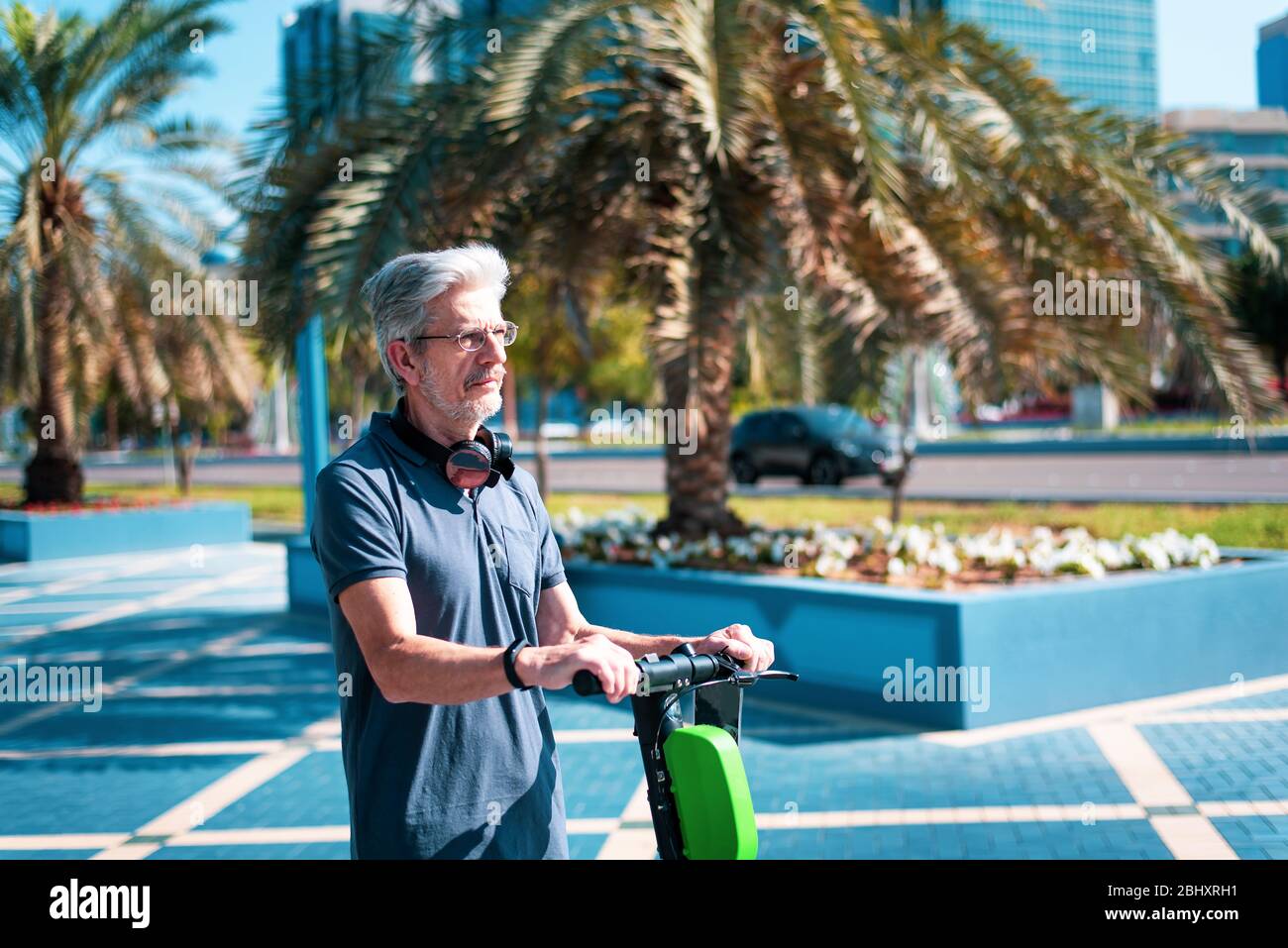 Senior che utilizzano scooter elettrico per il trasporto in un ambiente urbano moderno. Stile di vita sano e di alto livello all'aperto Foto Stock