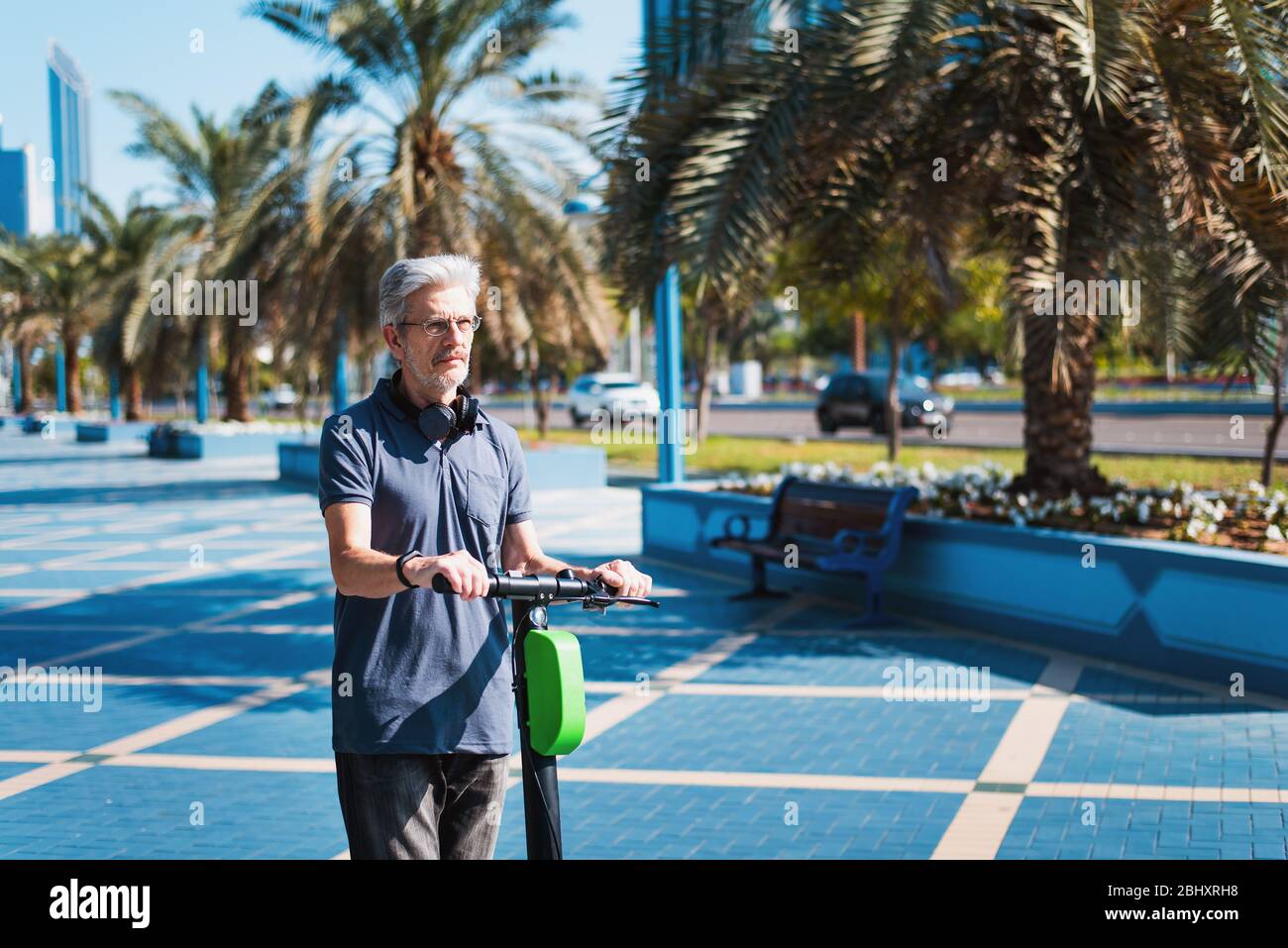 Senior che utilizzano scooter elettrico per il trasporto in un ambiente urbano moderno. Stile di vita sano e di alto livello all'aperto Foto Stock