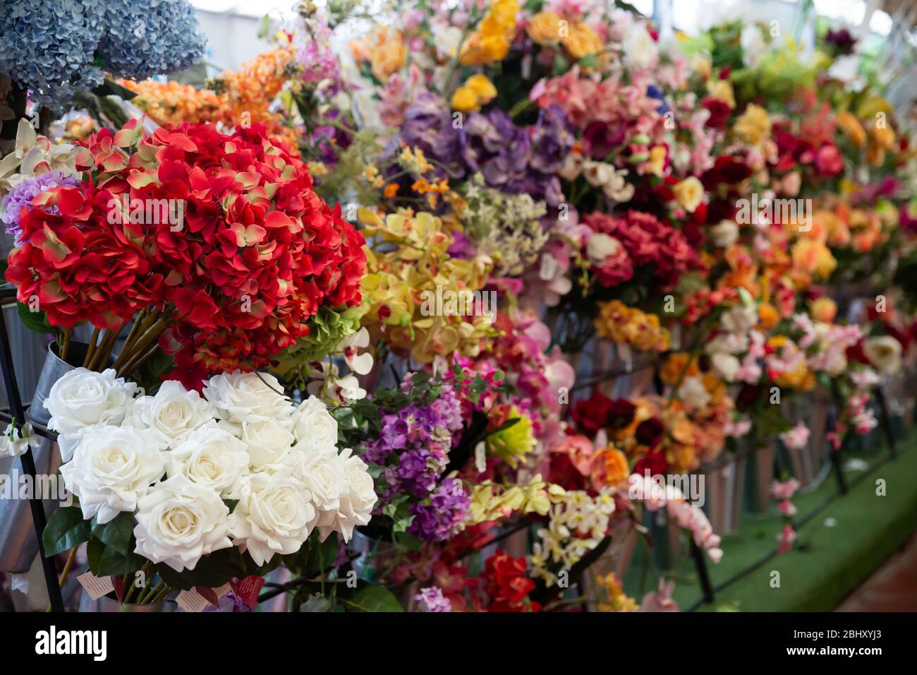 Vetrina colorata di fioreria con ampio assortimento di fiori artificiali Foto Stock