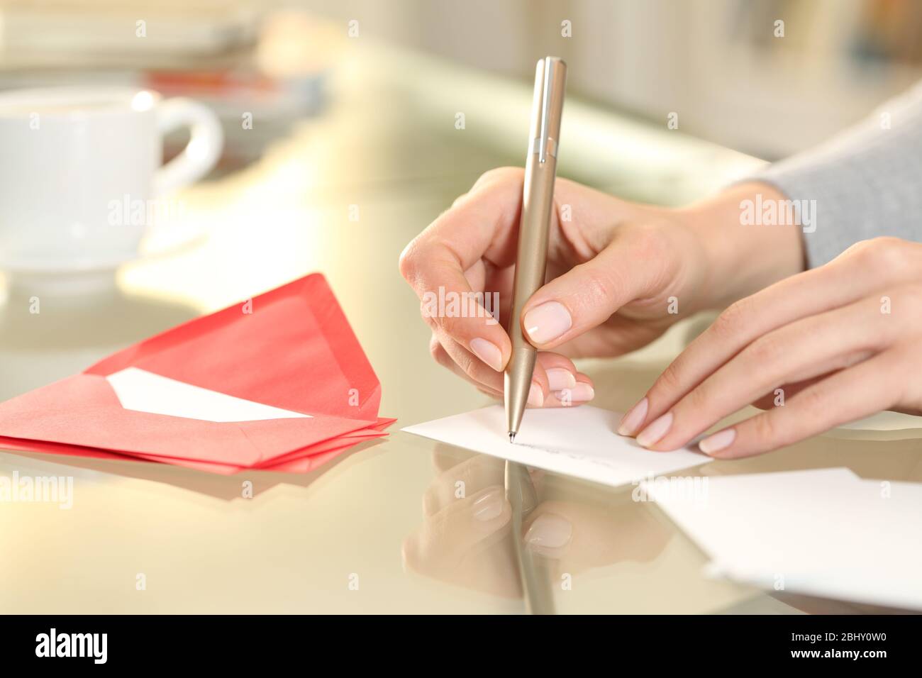 Primo piano di donna mano di scrittura saluto grazie scheda seduto su una scrivania a casa Foto Stock