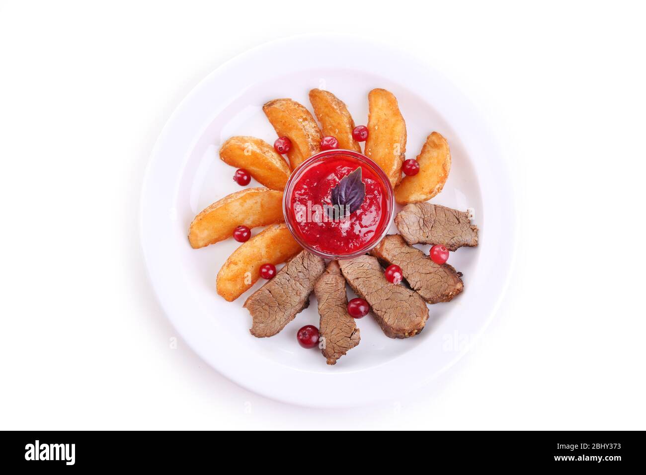 Manzo con salsa di mirtilli rossi, fette di patate arrostite su piatto, isolato su bianco Foto Stock