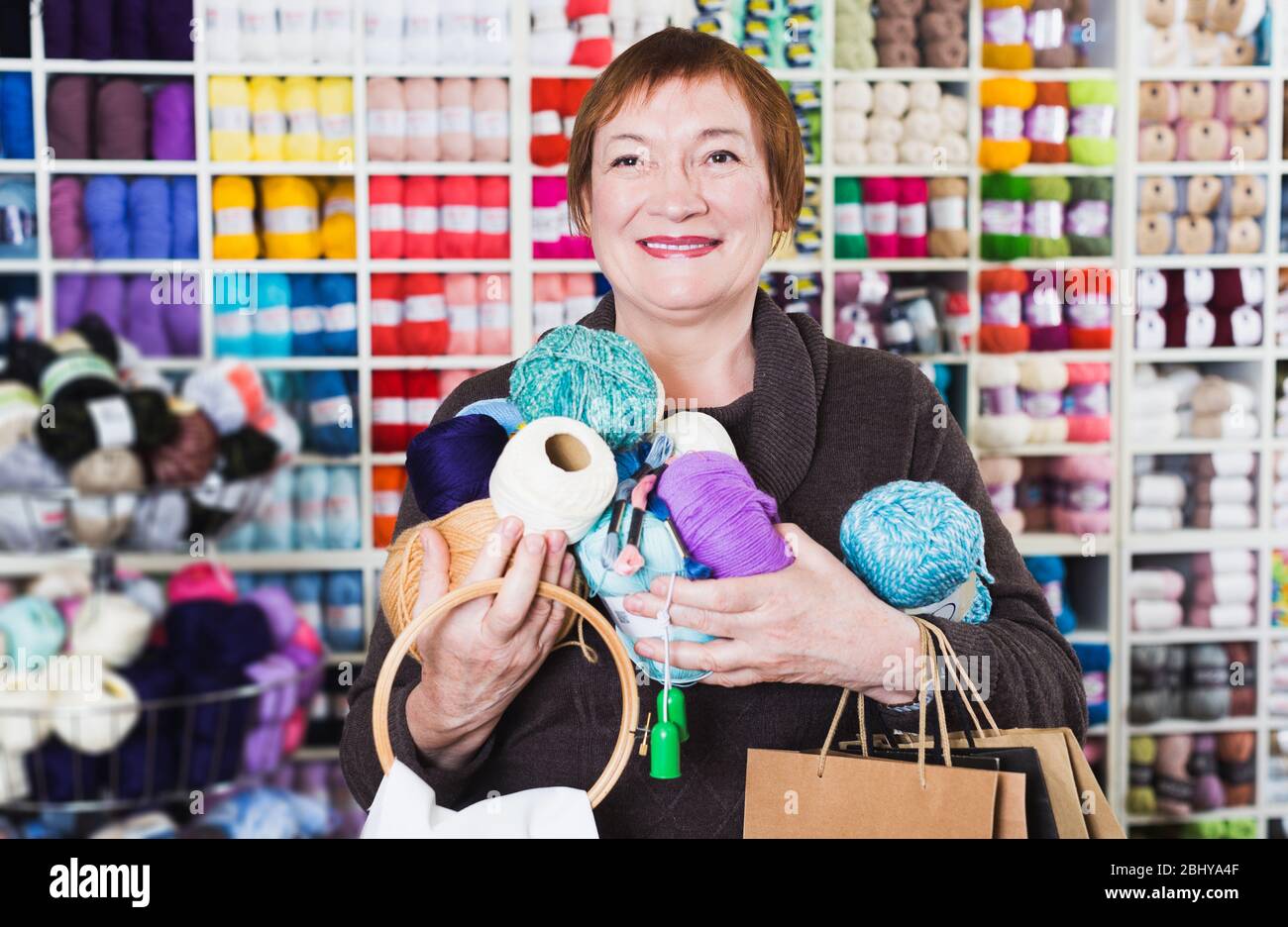 Felice senior donna con le borse della spesa usando il telefono nel ripostiglio store Foto Stock