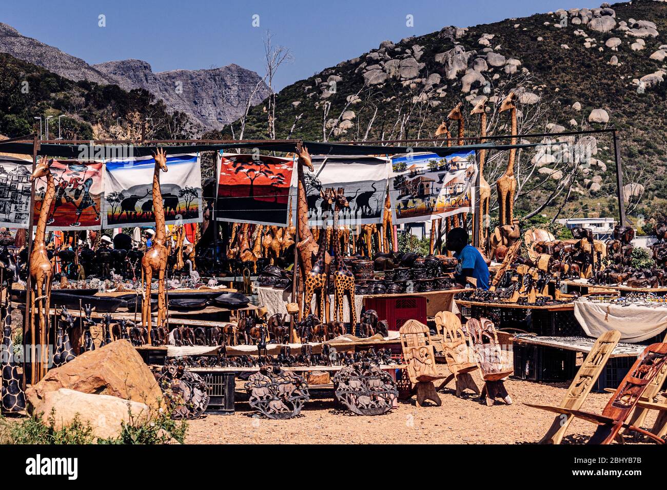 Uomo africano che vende sculture in legno artigianali e souvenir turistici da laybye a chapmans Peak Drive Città del Capo Sud Africa Foto Stock