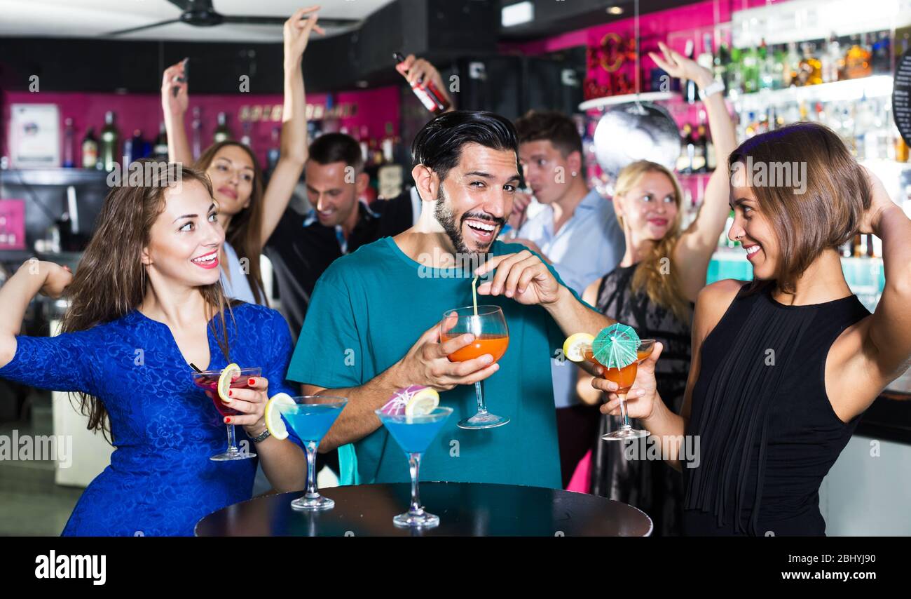 Le donne con l'uomo bevono cocktail e si divertono nel nightclub Foto Stock