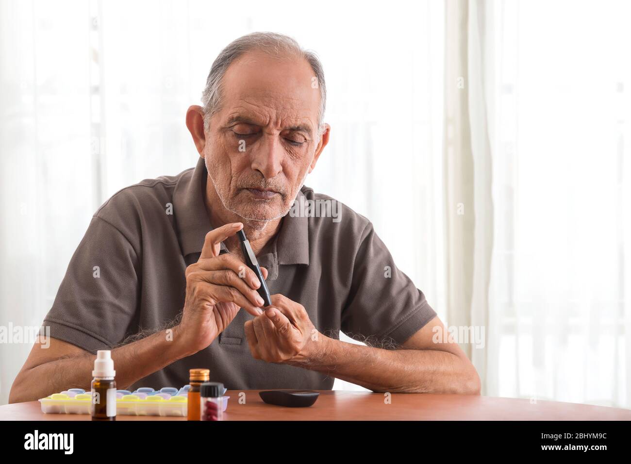 Uomo anziano che prende il suo test del diabete a casa. (Salute e fitness) Foto Stock