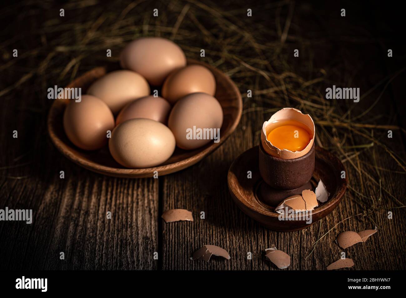 Uova brune intere e rotte su tavola di legno Foto Stock