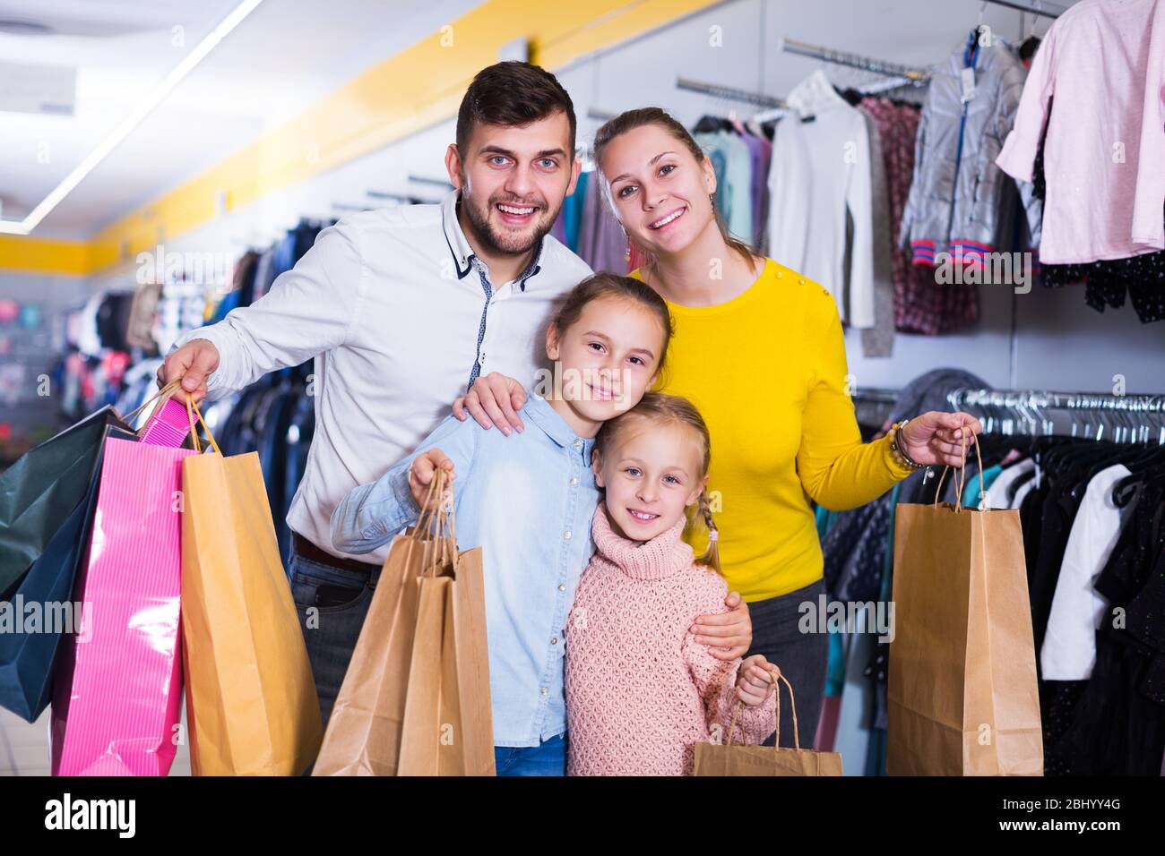 Giovani felici i genitori con due bambine durante la famiglia shopping Foto Stock