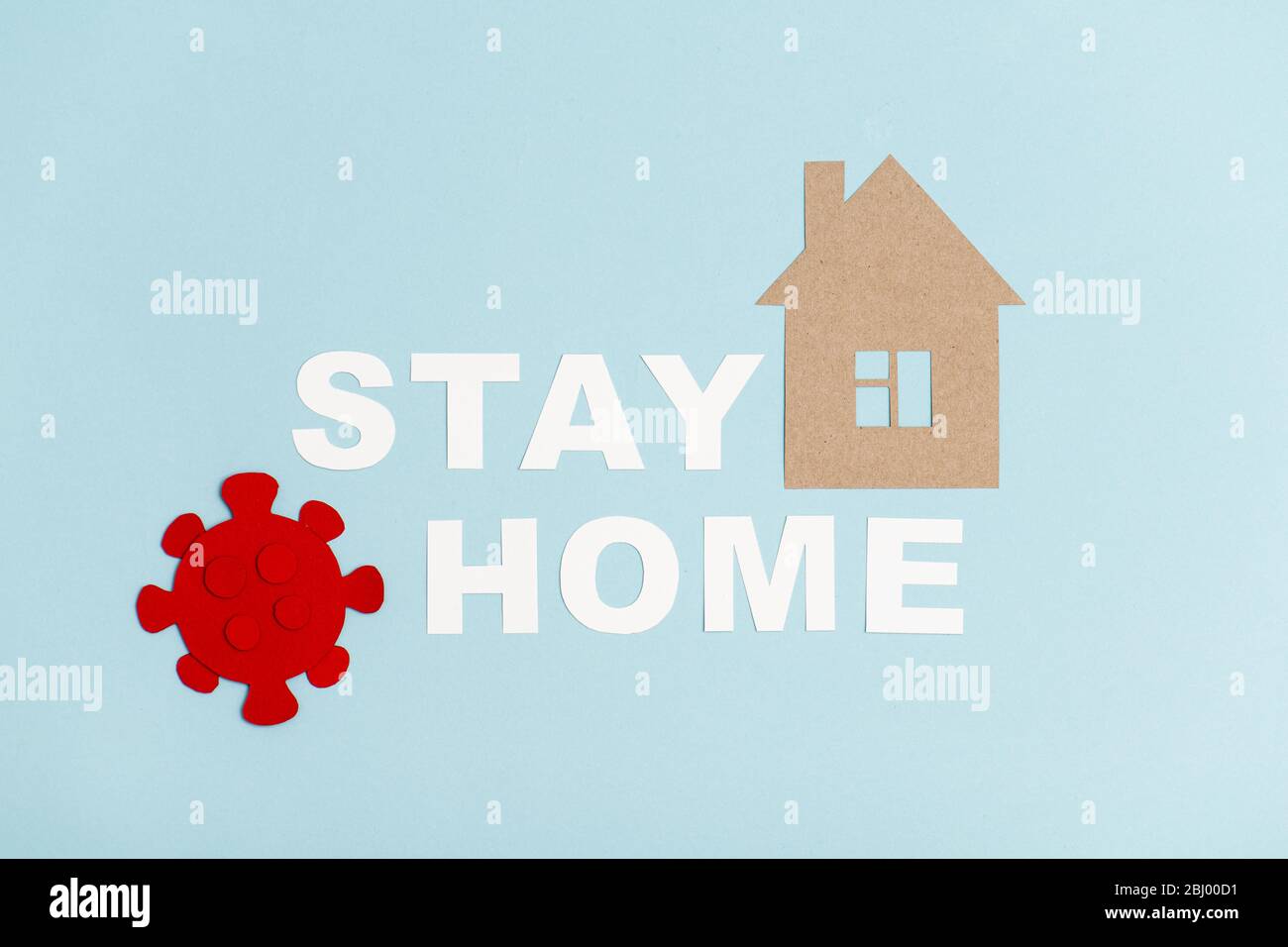 Forma di coronavirus rosso accanto a rimanere messaggio di casa con la forma della casa Foto Stock