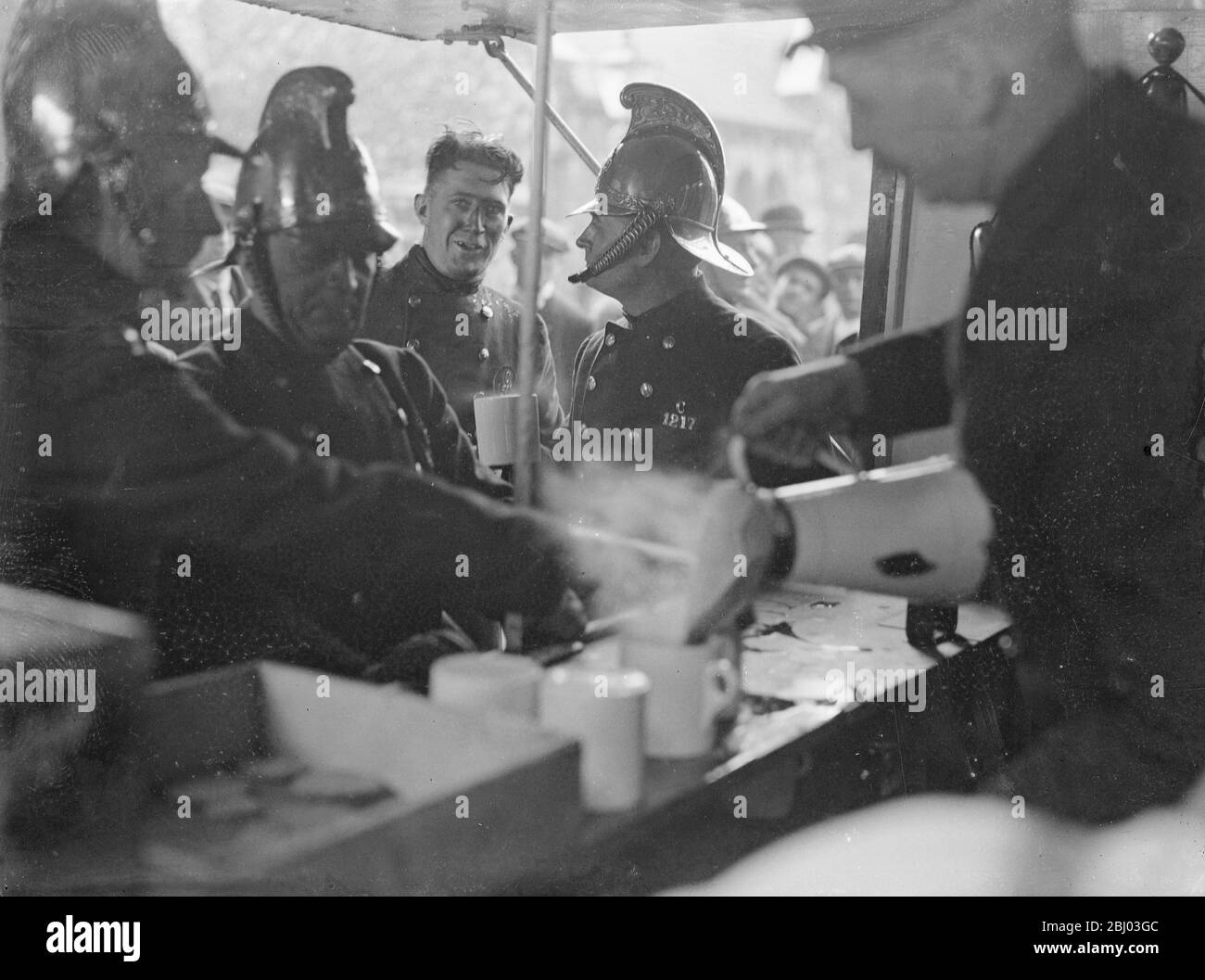 Pompieri rinfrescarsi con una tazza di tè dopo aver combattuto il fuoco di gomma di scarto . - 29 ottobre 1934 - - Foto Stock
