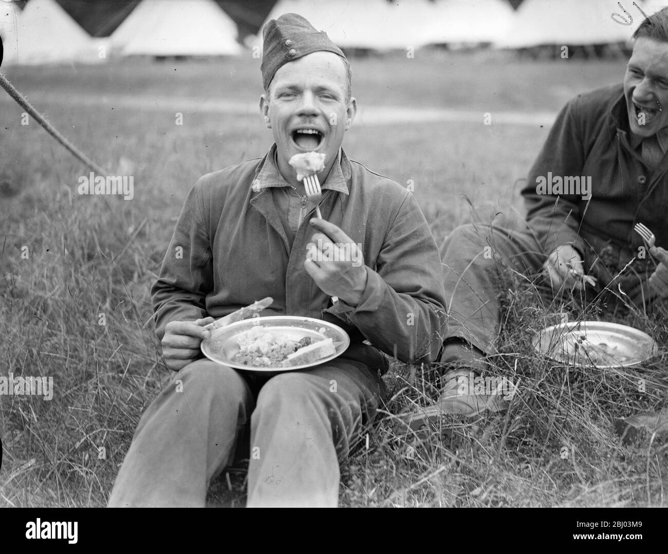 Uno degli ospiti civili che si godono un pasto. 15 giovani provenienti da Londra meridionale trascorrono due settimane di vacanza gratis come ospiti del 23° London Regiment (il Surrey orientale) nel campo annuale di Arundel Park, Sussex. - 26 luglio 1937. - Foto Stock