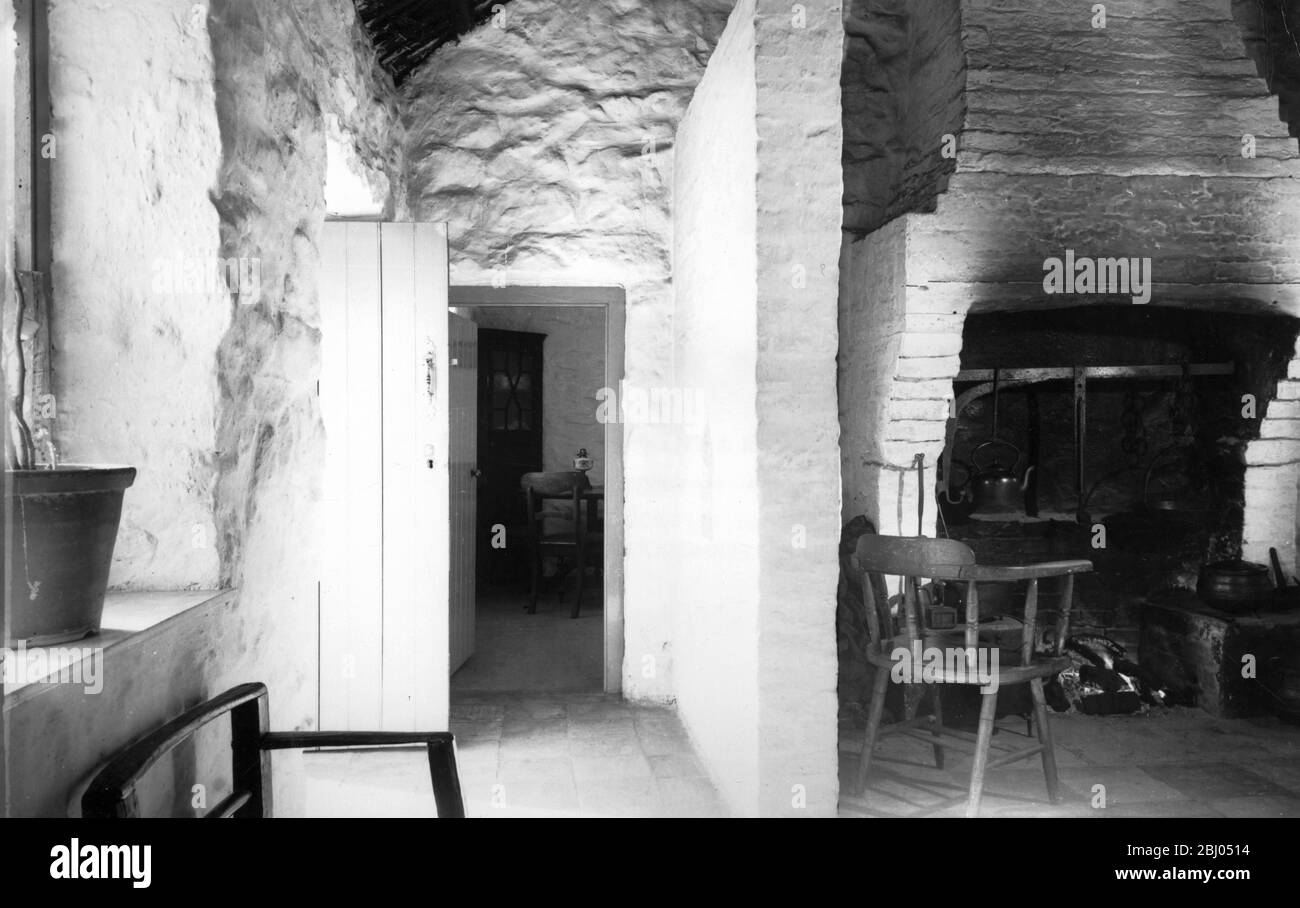 Cucina interno nella casa colonica di Corradreenan townland West County Fermanagh, ora presso l'Ulster Folk Museum. La porta dall'esterno e la cucina focolare sono in linea con l un l altro così essi sono separati dallo stipite montato a parete con la sua piccola finestra spia. La sostanziale ciminiera in mattoni non è una caratteristica originale, ma sostituisce una argilla intonacata camino di vimini, il mattone camino è uno di un numero di ottocento miglioramenti incorporati nella casa, un altro è il pavimento in mattonelle Foto Stock