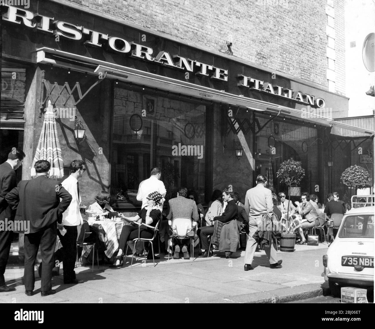 Il bar sul marciapiede a Londra - il sole è venuto a Londra questo pomeriggio - e alcuni sono persino andati a mangiare fuori - come in questo ristorante Kensington. - 11/4/64 - Foto Stock
