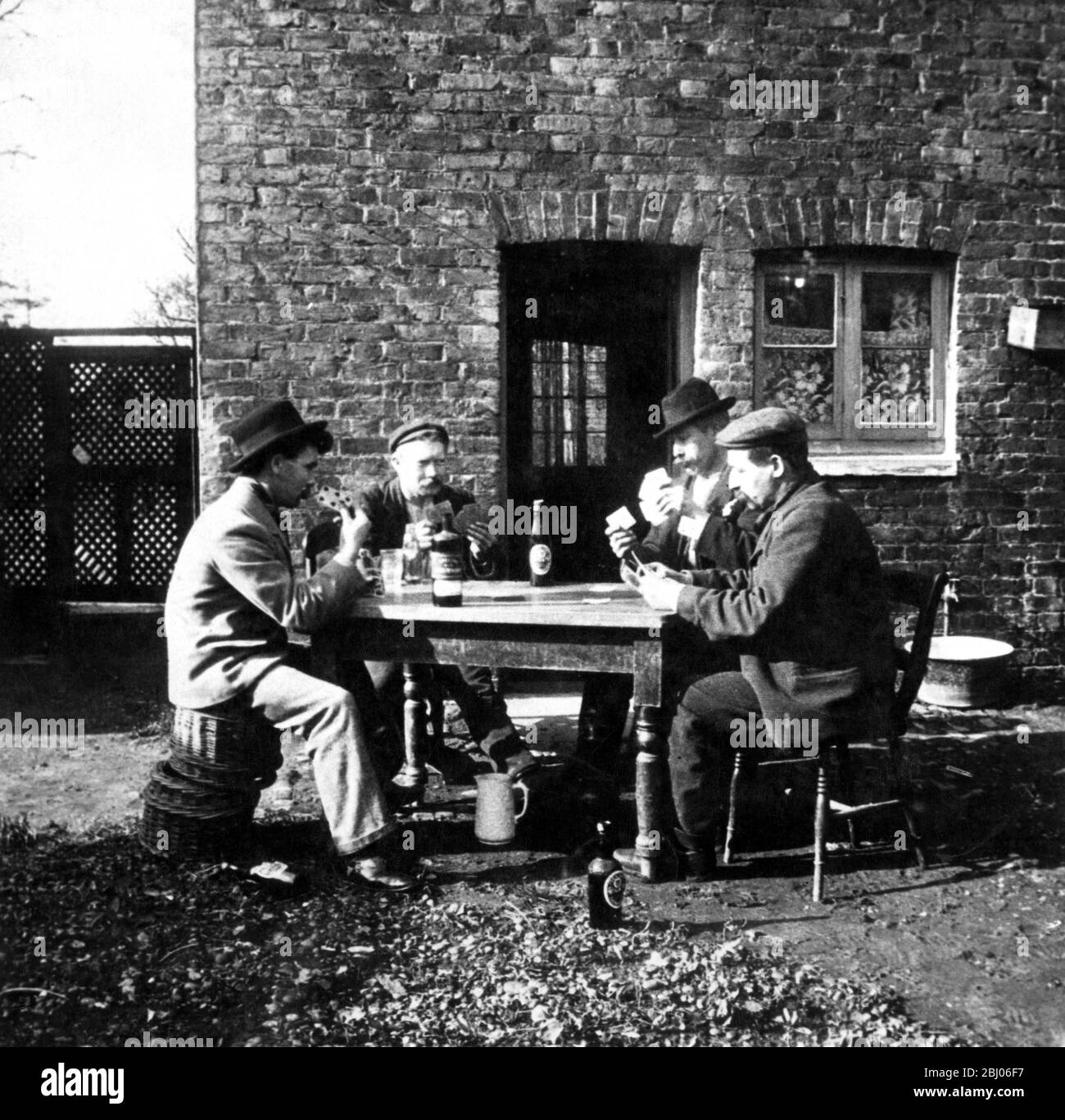 Gli uomini che bevono fuori di un pub mentre giocano le carte Foto Stock