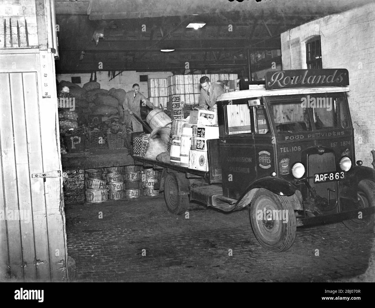 Rowlands - fornitori di cibo che caricano il loro camion con greengrocery per la consegna. - 1937 Foto Stock