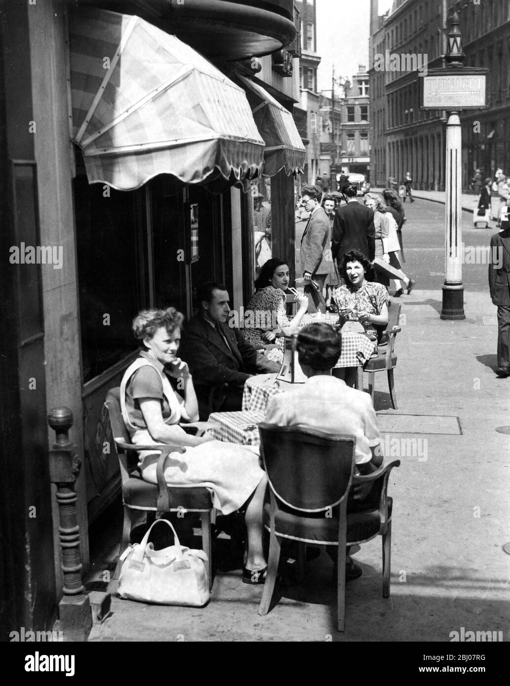 I visitatori di Londra possono gustare uno spuntino e una bevanda in stile veramente continentale al caffè all'aperto di Oxford Street; l'enorme tenda offre una certa protezione rinfrescante dal sole, Londra , Inghilterra . - 31 maggio 1947 Foto Stock