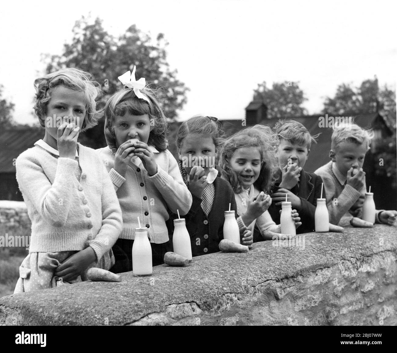 Un gruppo di bambini al Chedworth , Gloucestershire , scuola del villaggio godere le loro mele prima di mangiare carote e lavarlo giù con latte . - 7 giugno 1961 Foto Stock