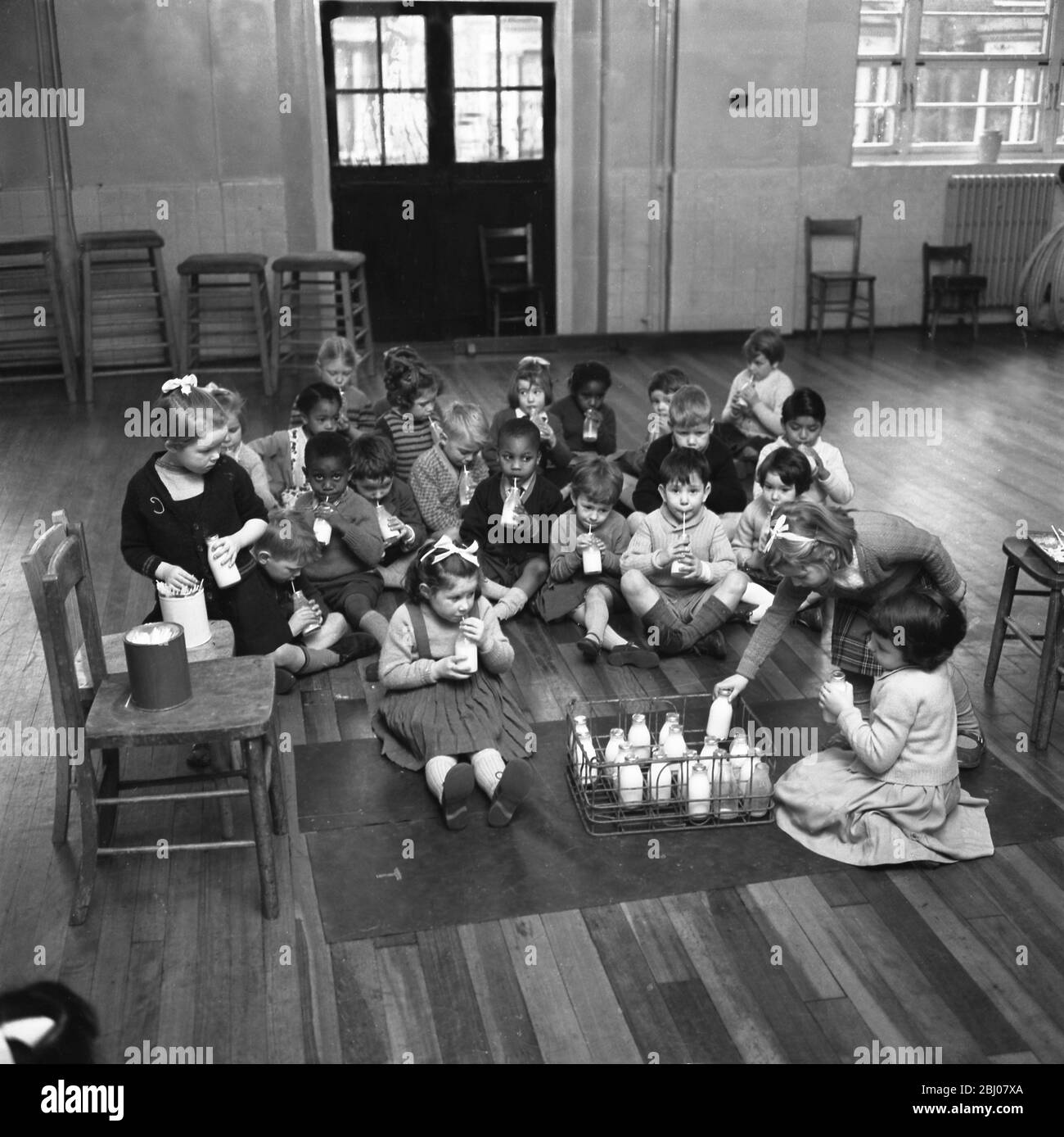 Durante una pausa nella giornata, questi bambini della Jessop Primary School , Herne Hill , a sud-est di Londra, godono di una bottiglia di latte nella sala della scuola . - 12 gennaio 1961 Foto Stock