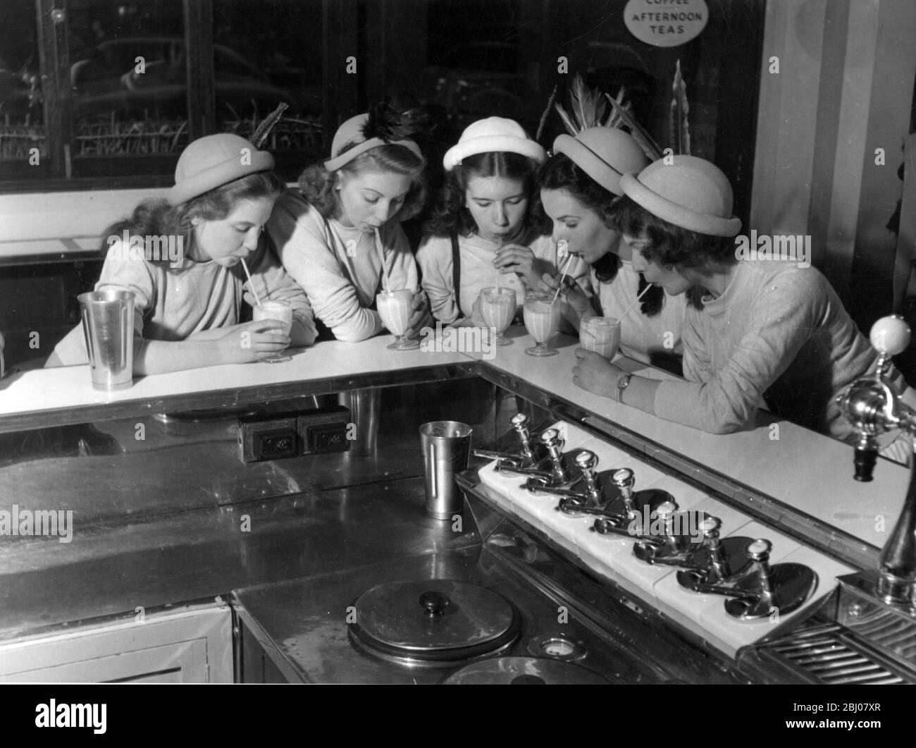 Giovani ragazze che bevono milkshakes sul bancone di una barretta di latte a Londra, Inghilterra - 11 luglio 1949 Foto Stock