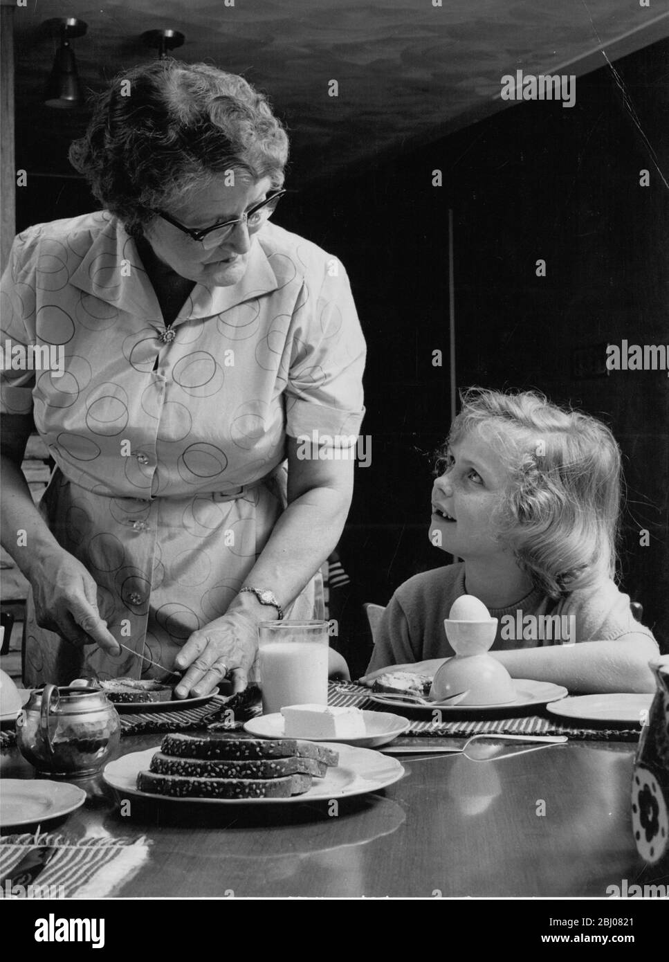 Questa bambina ama passare il tempo con la nonna soprattutto per la colazione quando si tratta di uova bollite e toast caldo al burro. - 8 aprile 1961 Foto Stock