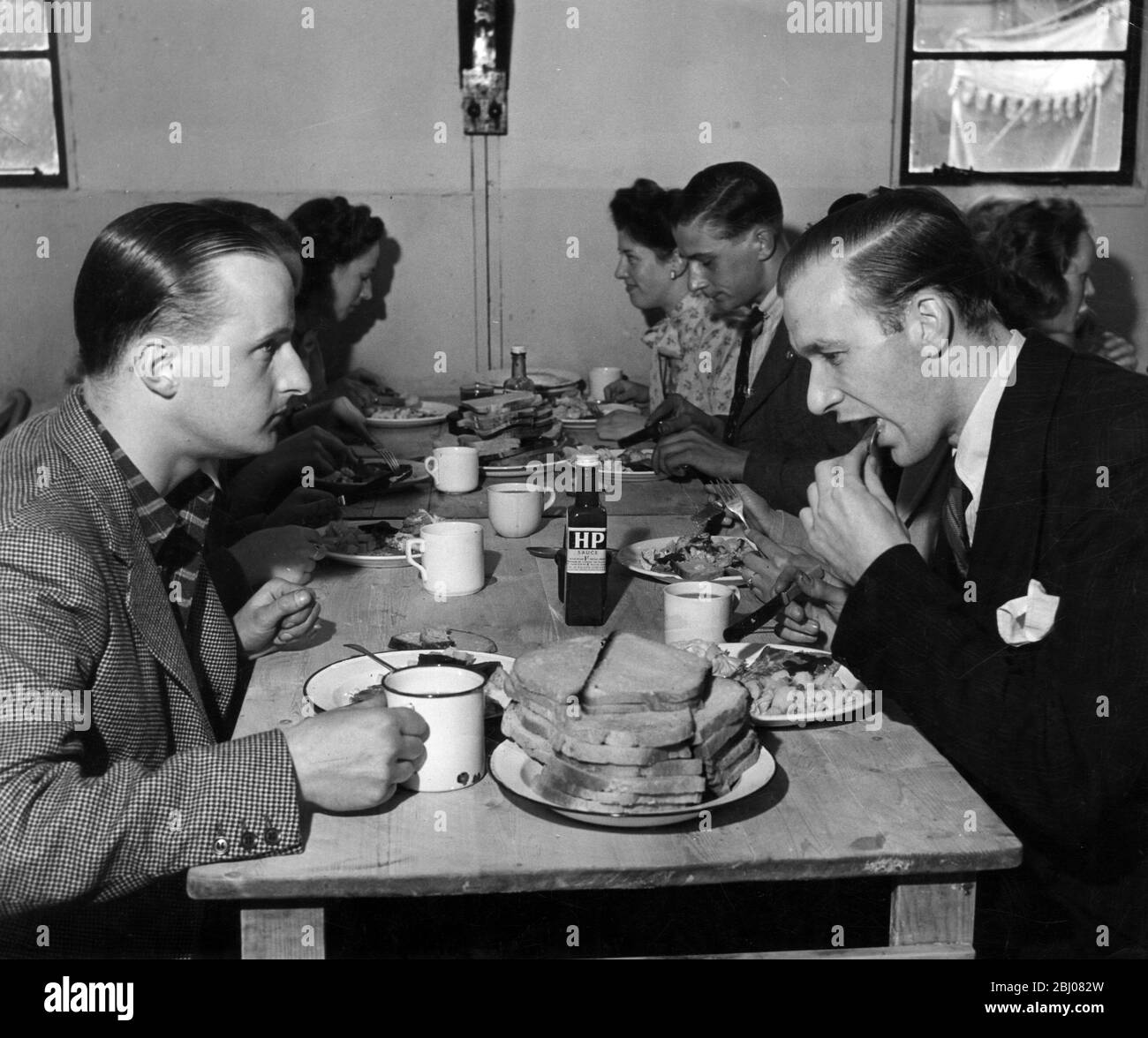 Lavori di fattoria volontari mangiare un pasto alla mensa dopo aver salvato il raccolto corrente nera a Home Farm, Shackleford, Surrey. Quando i POW tedeschi sono stati redatti a casa una carenza di manodopera ha portato al Ministero dell'Agricoltura a chiedere a 150,000 volontari di rinunciare alle loro vacanze estive e di dare una mano sulla Terra. 2 agosto 1947 - Foto Stock