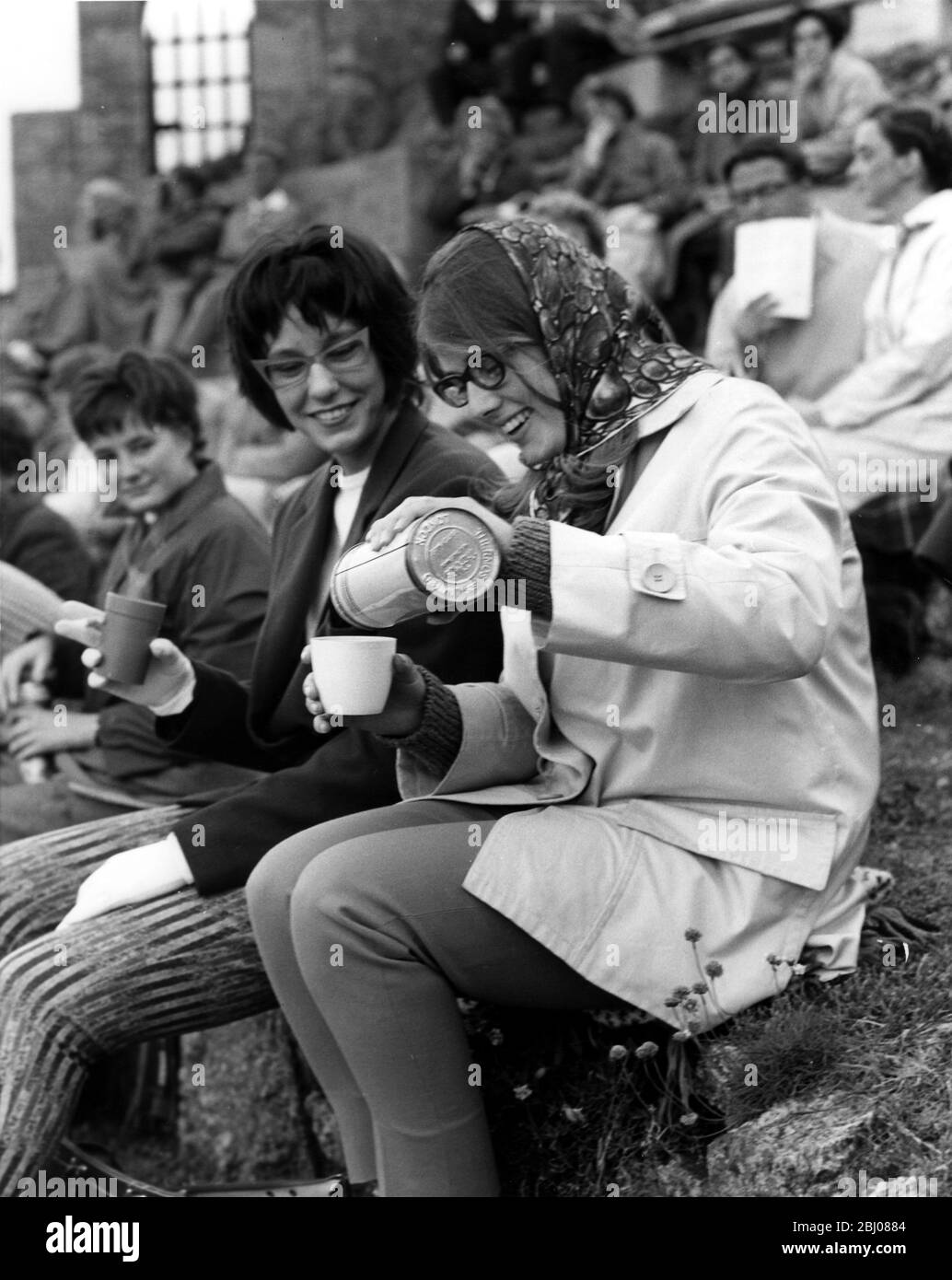 I membri del pubblico al teatro all'aperto Minack sulla cima della scogliera della Cornovaglia a Porthcurno , Cornovaglia , Inghilterra , sono invitati a prendere i loro rinfreschi per l'intervallo , e a fuga fredda , un pallone da vuoto contenente una bevanda calda è un utile accessorio per il teatrino . Queste due giovani donne, Britt-Mari Fock (a sinistra) ed Elisabeth Jansson , sono studenti della Svezia - luglio 1962 Foto Stock