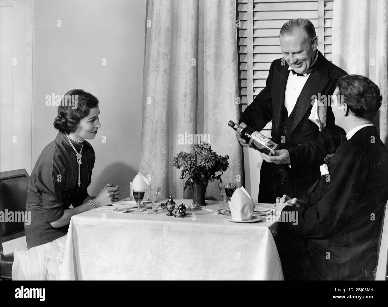 Un cameriere di vino mostra una bottiglia a un cliente. - 24 novembre 1949 Foto Stock
