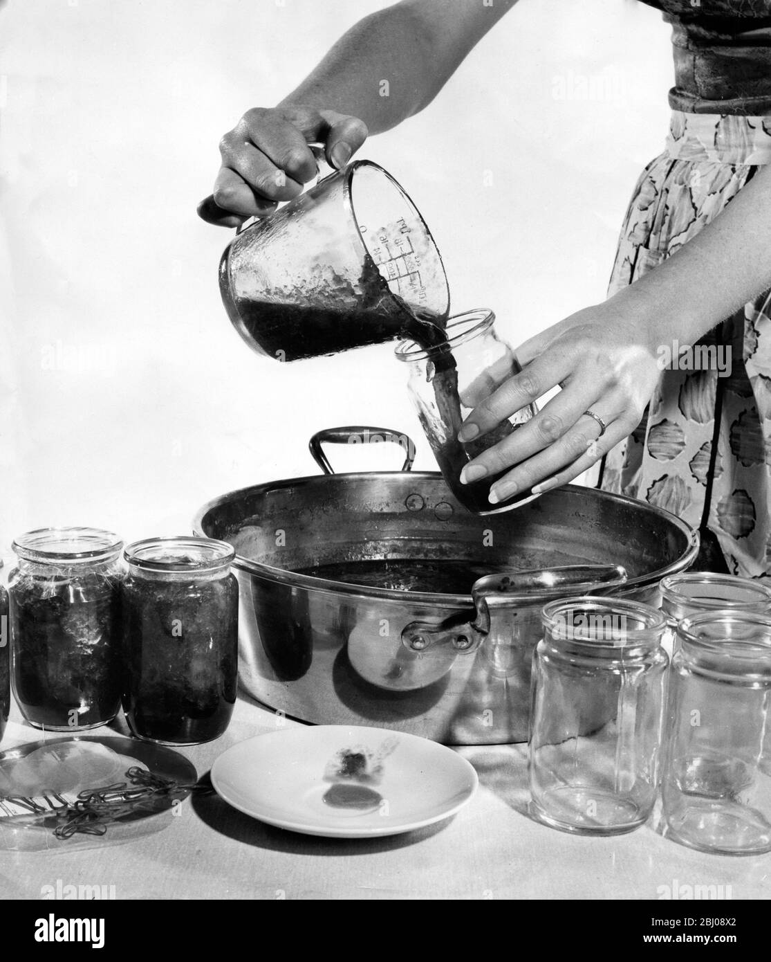Marmellata che fa - versando la marmellata leggermente raffreddata in vasetti - 1960 Foto Stock