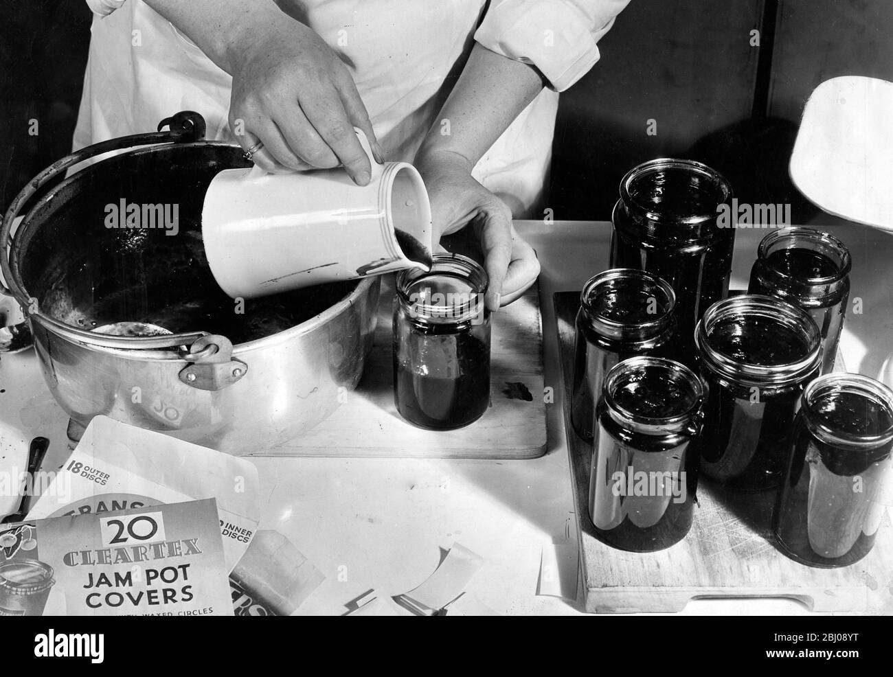 Marmellata che fa - versando la marmellata leggermente raffreddata in vasetti - 1940 Foto Stock