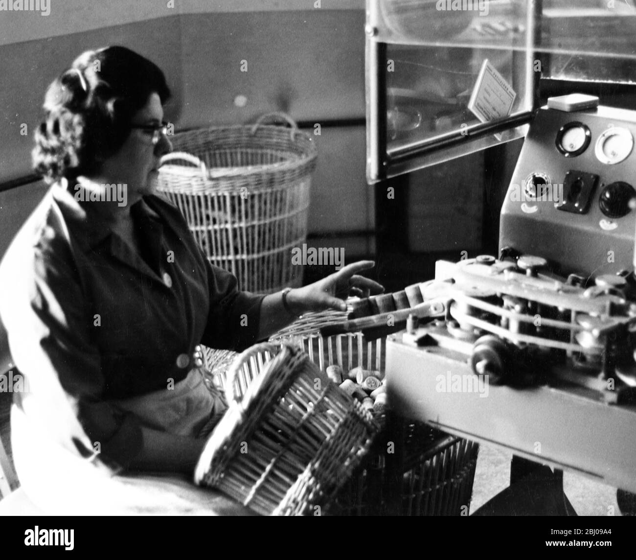 Donna operatrice in fabbrica Moet & Chandon che controlla i tappi di champagne uscenti dalla macchina di taglio automatica. Foto Stock