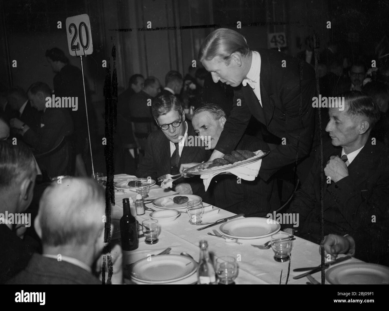 La carne di balene fu servita per la prima volta in un pranzo ufficiale a Londra, quando l'Institute of Refrigeration ha affondato il pranzo d'autunno presso le Connaught Rooms. Dopo il permesso del Ministero del cibo, l'hamburger di balene apparve sul menu come un piatto extra, descritto come essere nella natura di un esperimento. Circa 400 ospiti hanno assaggiato il nuovo piatto che è stato preparato e servito sulle stesse linee di un hamburger. - Picture show: Un cameriere che serve hamburger di balene a pranzo. - 29 novembre 1946 Foto Stock