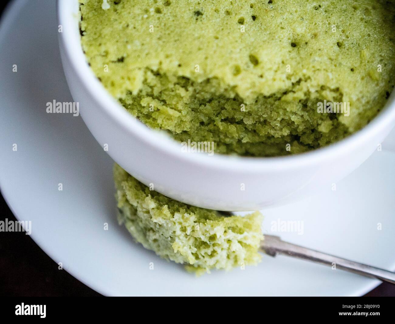 Deliziosa torta semplice fatta con mandorle macinate e polvere di tè verde matcha, cotta in una tazza in un forno a microonde. Foto Stock