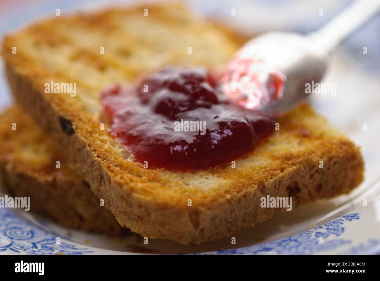 Marmellata fatta in casa su pane tostato fatto con pane senza glutine e cucchiaio d'argento Foto Stock