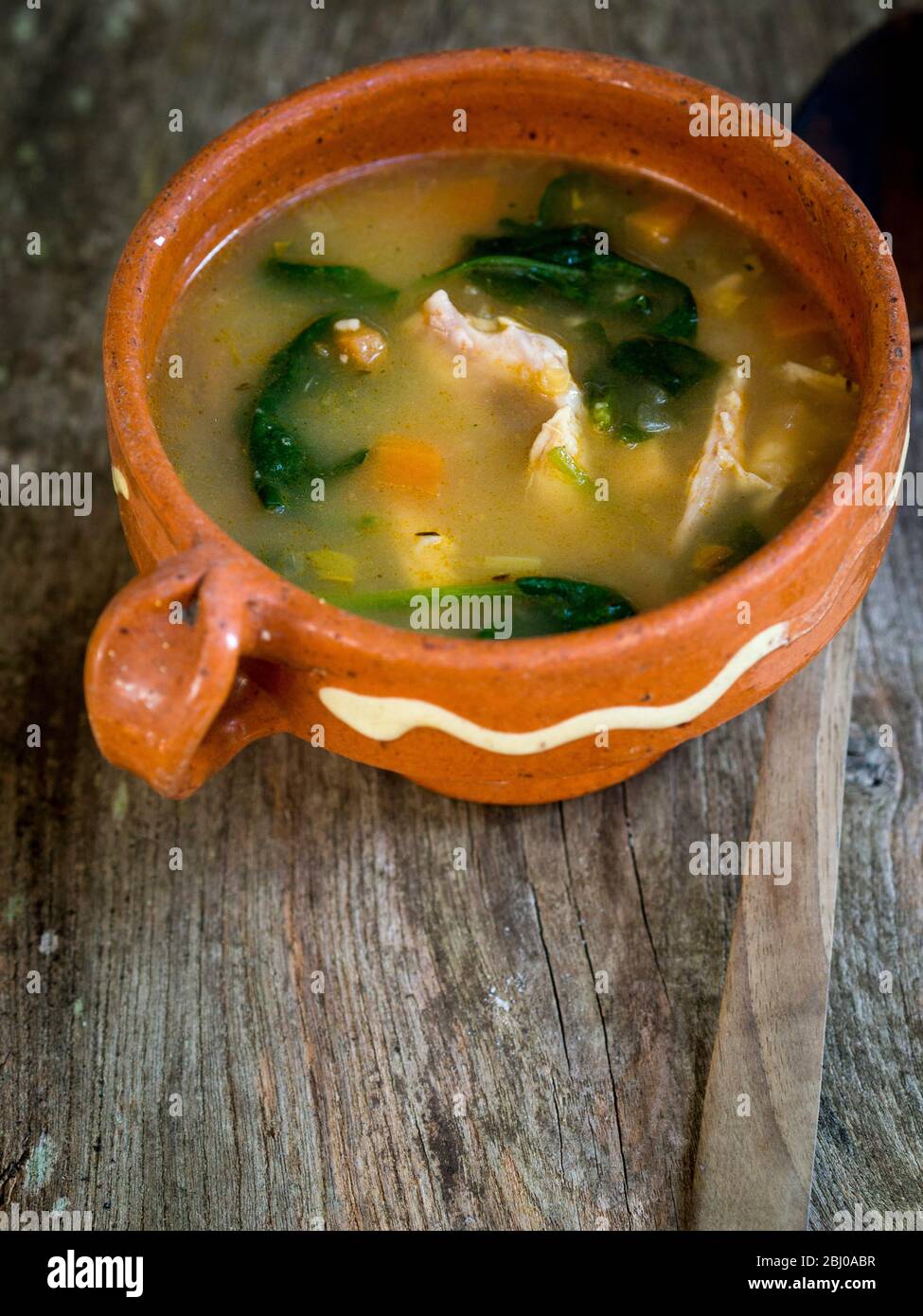 Un pasto completo la zuppa di pollo, il salame chorizo e verdure con riso marrone, Lenticchie e spinaci, servita in blu pallido ciotola Foto Stock