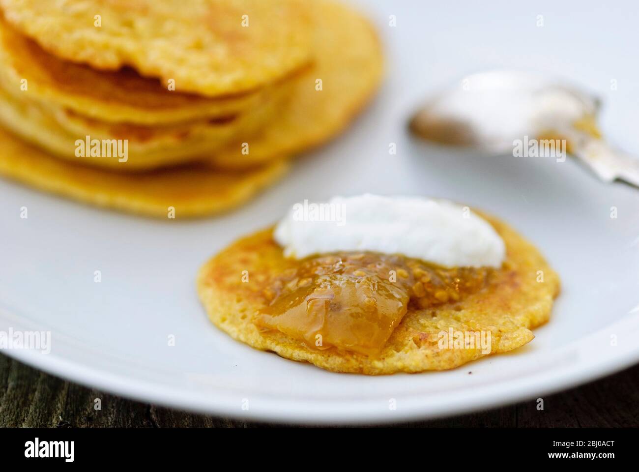 Pancake di piccole frittelle di farina di ceci indiana (chana dal), senza glutine e molto nutriente. Servito con chutney di lime e yogurt Foto Stock
