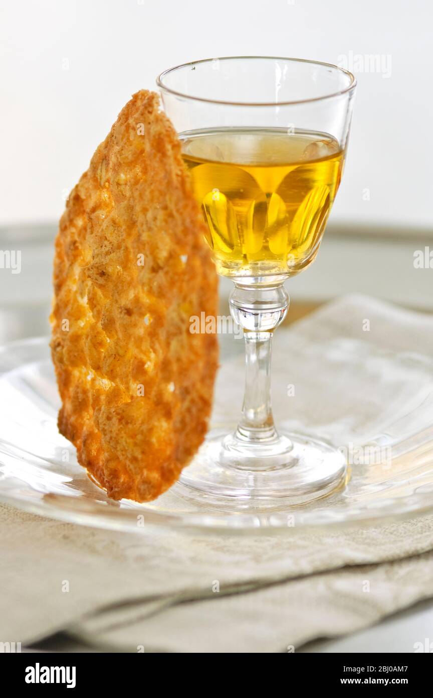 Biscotto tuile con un piccolo bicchiere di vino da dessert su un piatto di vetro - Foto Stock