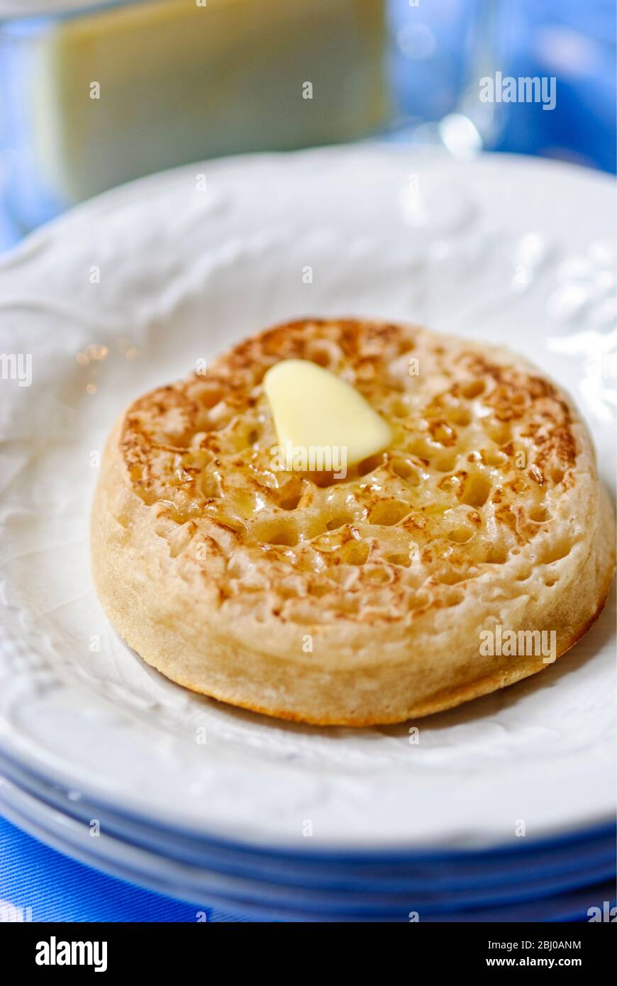 Tradizionale crumpet al burro caldo su piatto bianco - Foto Stock