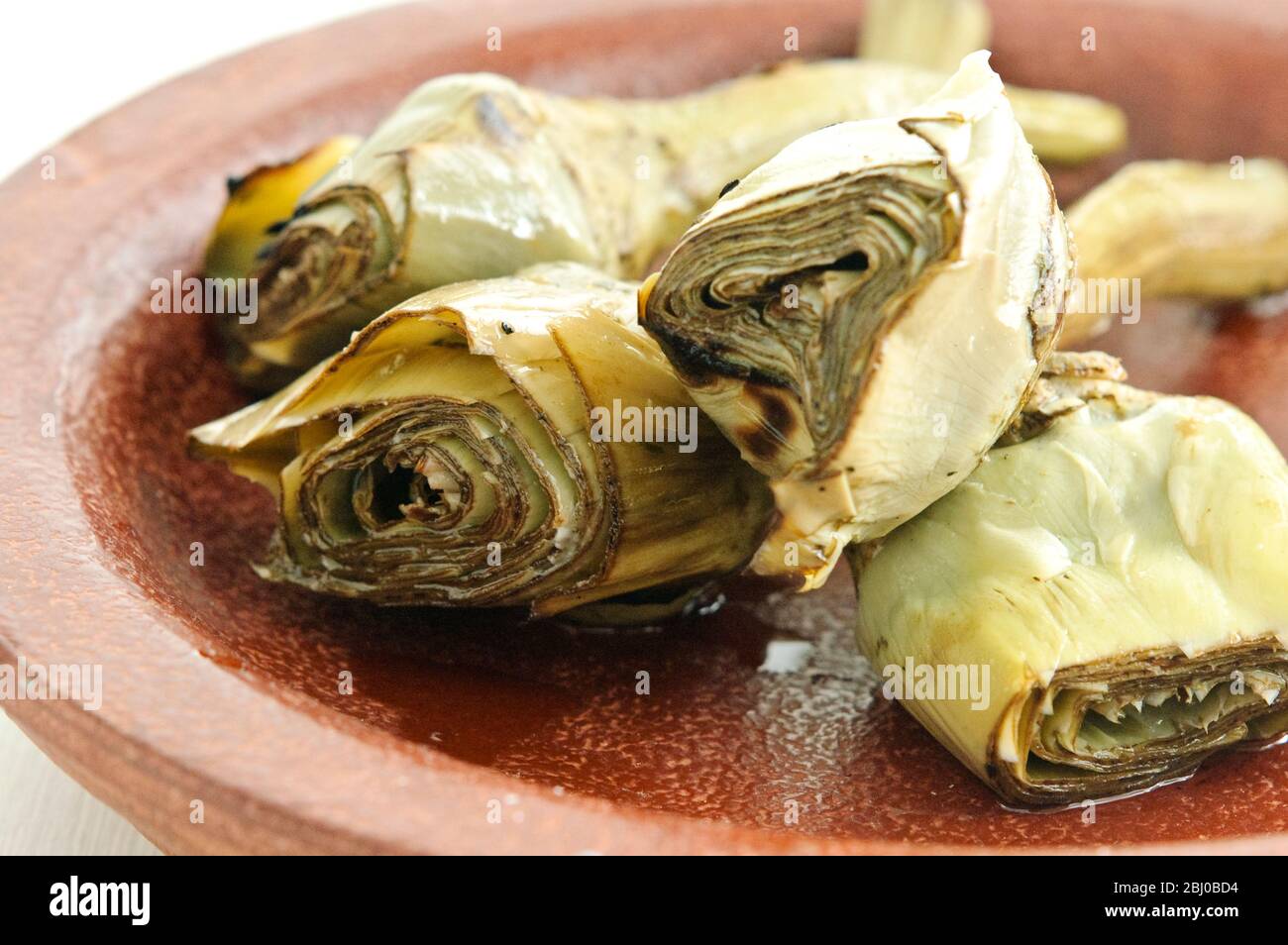 Carciofi italiani alla griglia e marinati su piatto marrone - Foto Stock