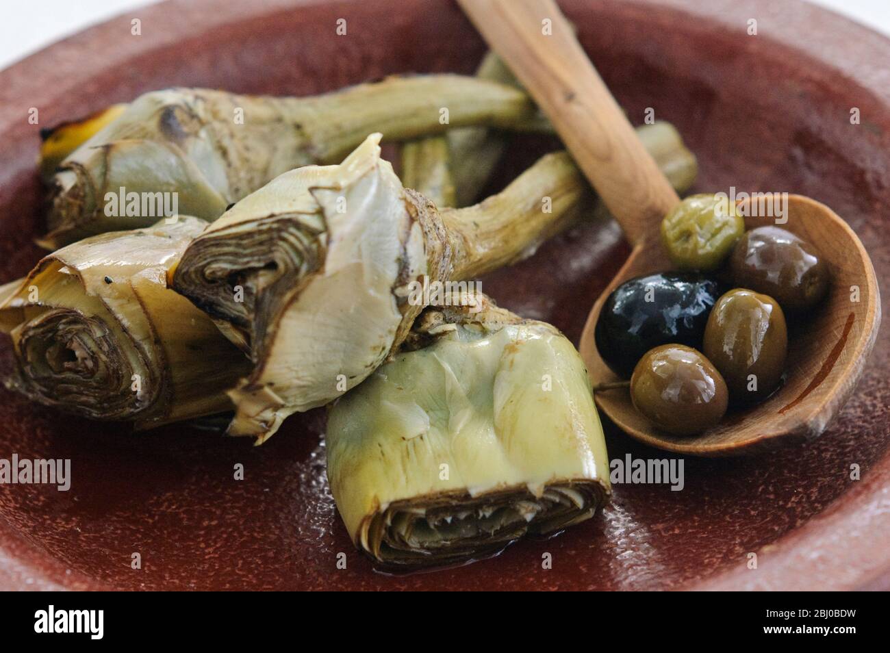 Carciofi italiani alla griglia e marinati su piatto marrone - Foto Stock