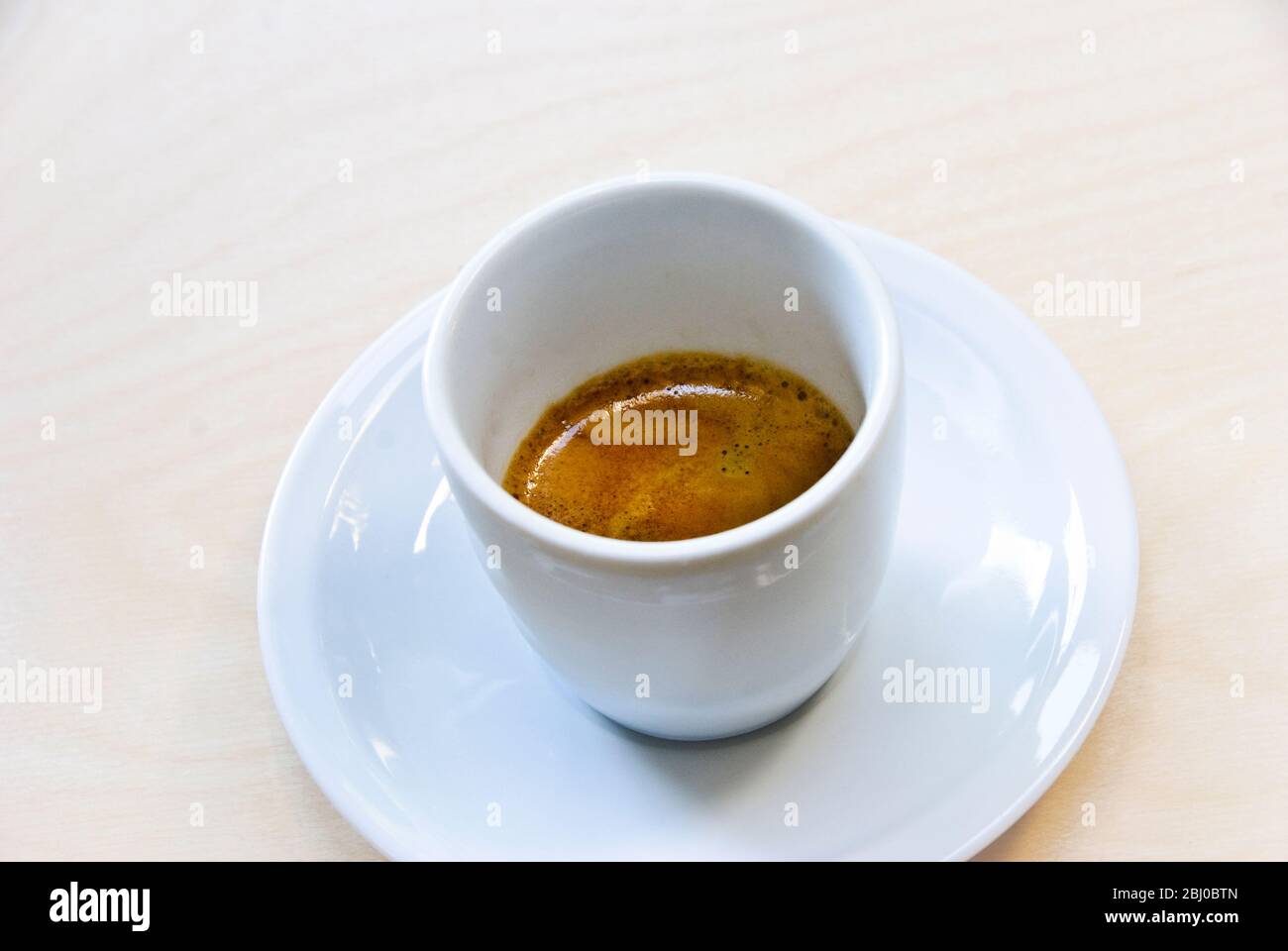 Tazza in porcellana bianca di caffè espresso appena preparato con le scarpe "creme" - Foto Stock