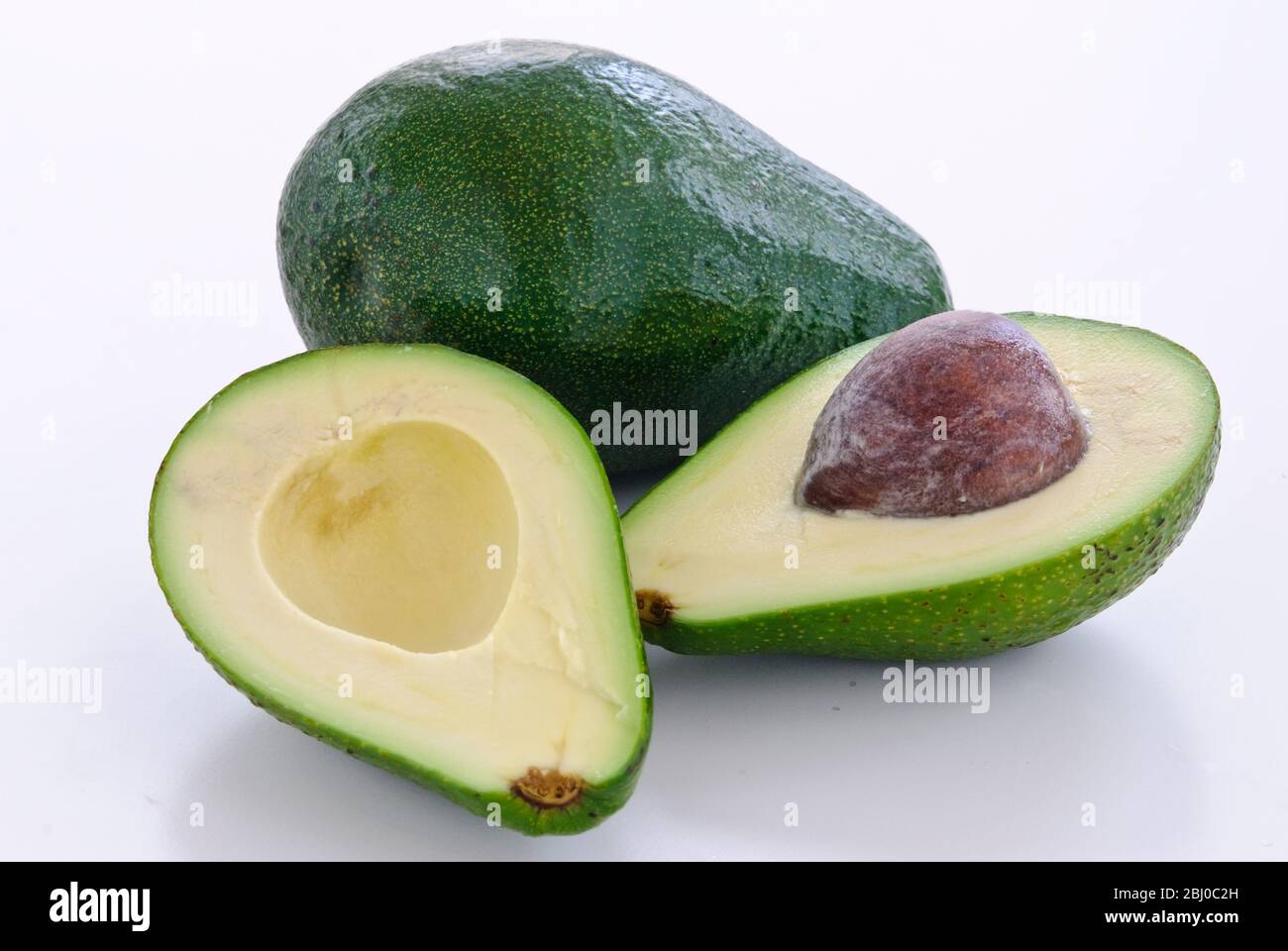 Pera di avocado fresca intera e tagliata su sfondo bianco - Foto Stock